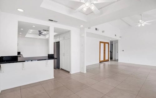 Black marble countertops and white living room in renovated home