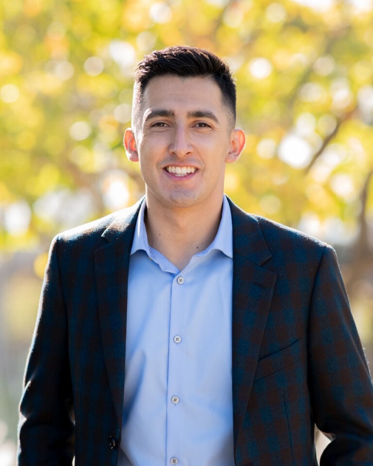 Professional profile photo of the owner of Ruiz Home Buyers smiling in business attire with a blurred outdoor background